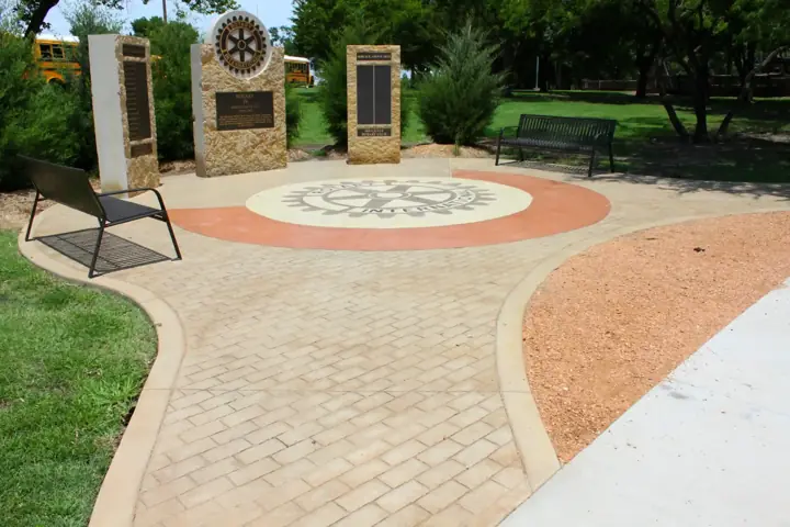Circular decorative concrete plaza with a brick pattern and colored band in Little Elm, TX
