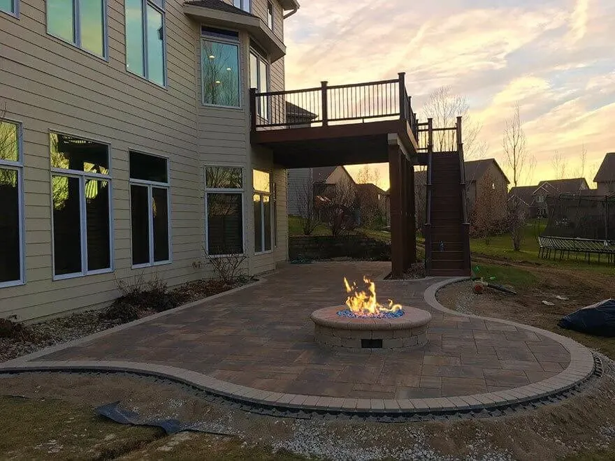 Curved concrete patio with a fire pit behind a two-story home in Little Elm, TX