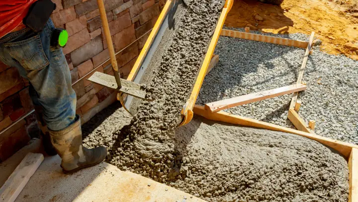 Crew screeding a fresh concrete slab inside wood forms for a boat pad in Little Elm, TX