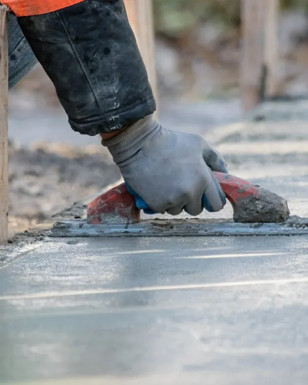 Gloved hand troweling a fresh concrete overlay on a patio in Little Elm, TX